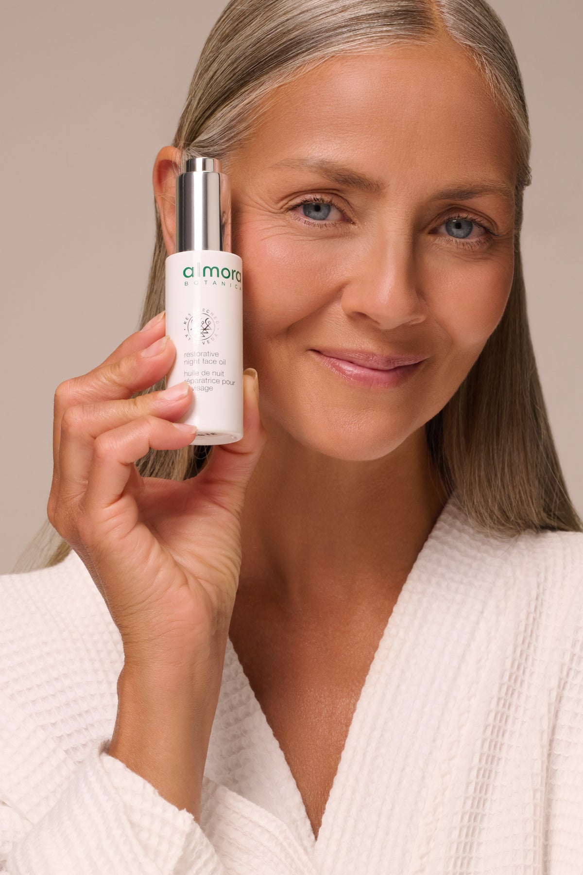 Woman holding a bottle of Restorative Night Face Oil to her cheek